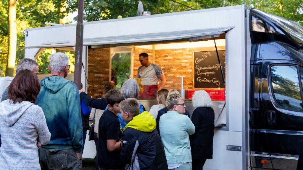 Hungrige Gäste freuen sich am Foodtruck auf das leckere Grillbuffet